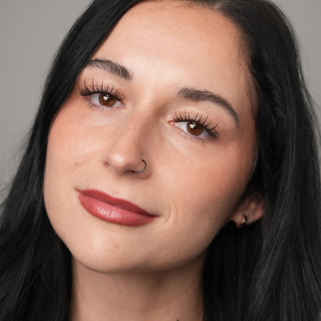 Close-up of a woman with dark hair and brown eyes against a neutral background